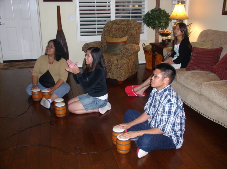 people sitting around in the living room playing games with nintendo wii controllers