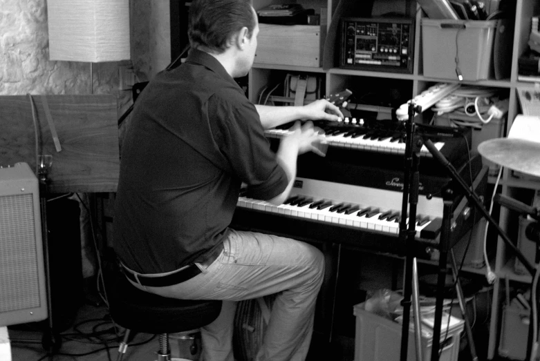 the man is at the keyboard playing an electronic organ