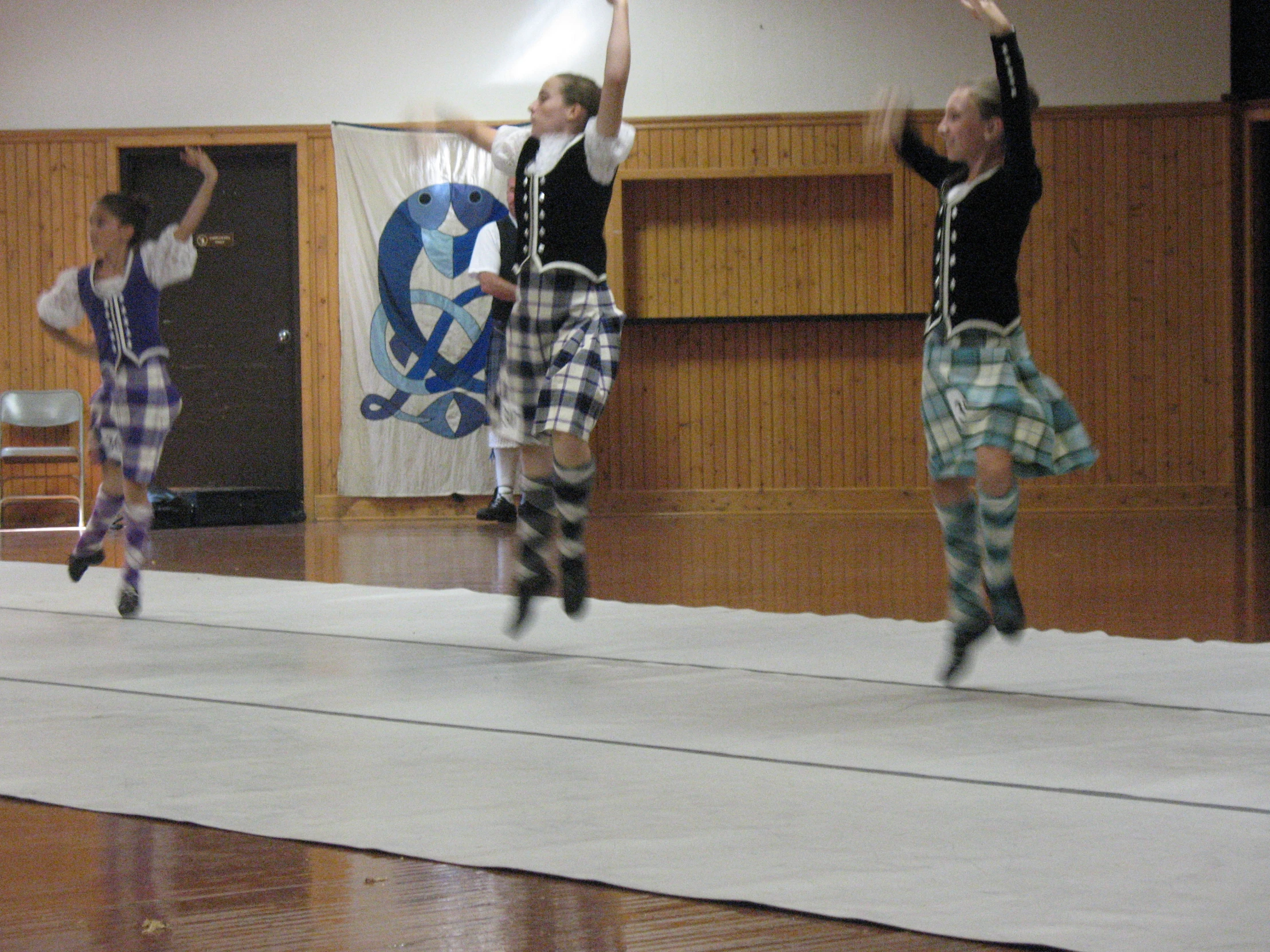 three people in scottish kilts jumping into the air