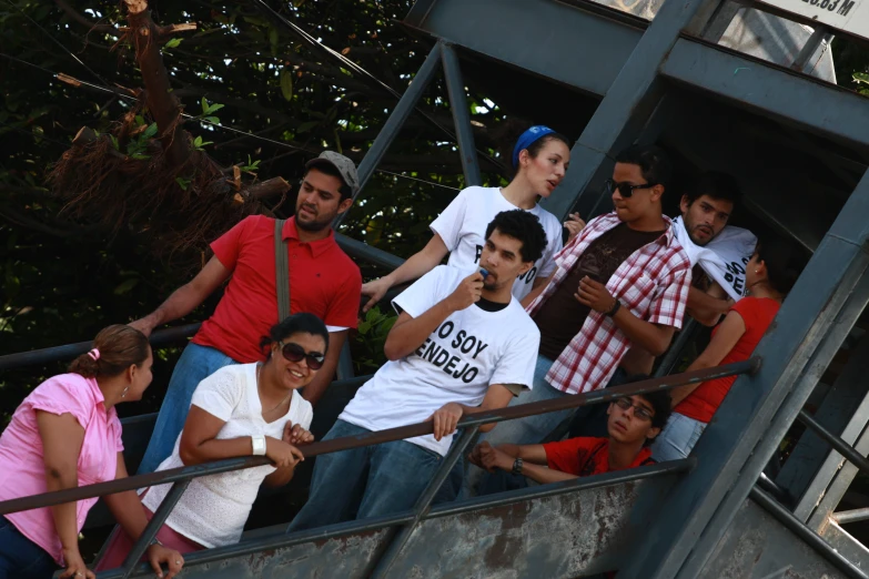 people in the middle of a balcony, some wearing t - shirts and sunglasses