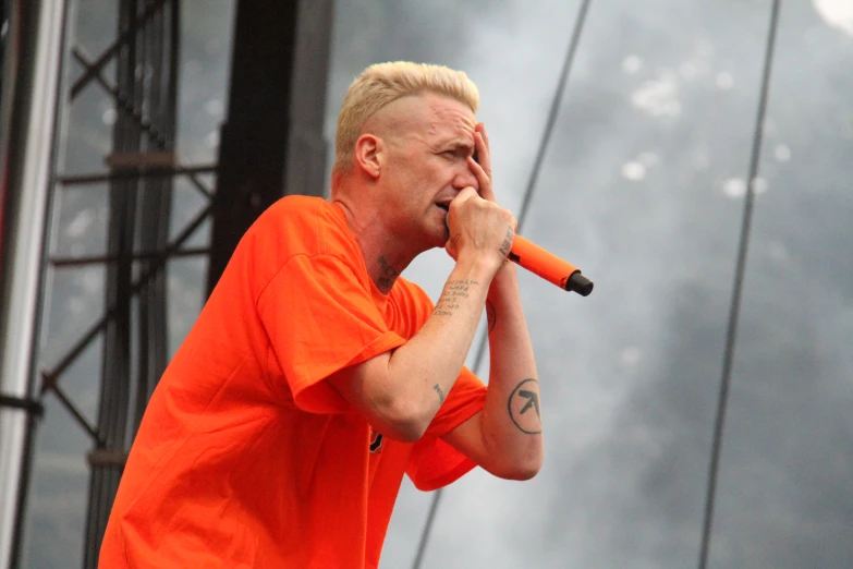a man with blonde hair and tattoos holding an microphone