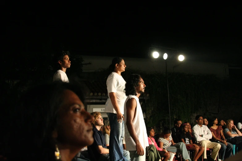 people watching an outdoor runway show at night