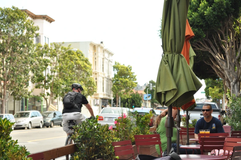 a man riding his bicycle near many tables and chairs