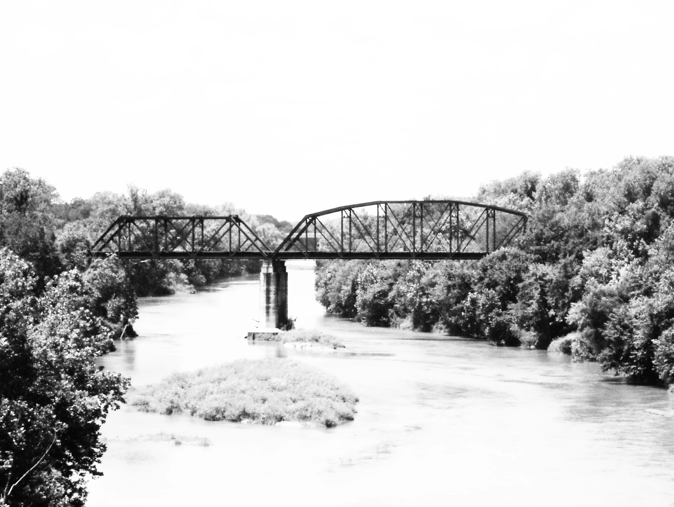 a bridge over a river with trees on either side