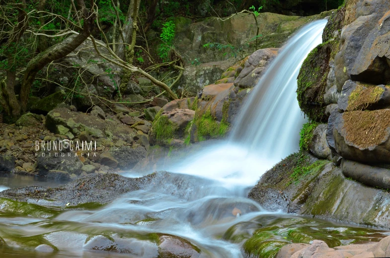 a big waterfall with lots of green rocks