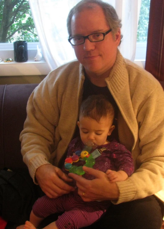 a man holds his daughter in his arms while looking at her phone