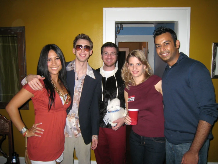 four people are posing together, with one person wearing sunglasses