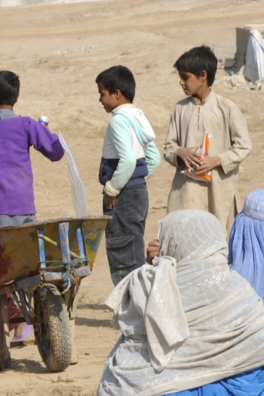 children in afghan clothing stand and talk with someone