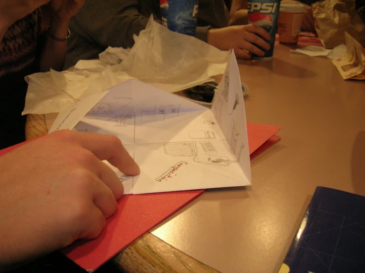 someone opening up some paper at a table