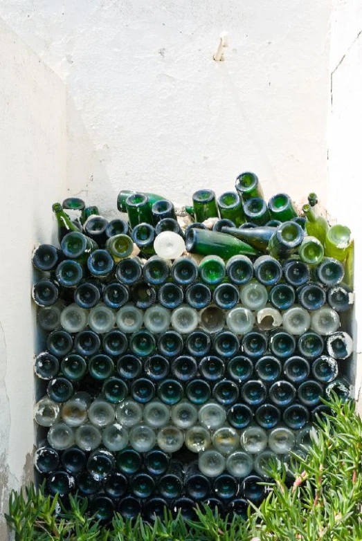 green bottles on top of a white wall with green moss