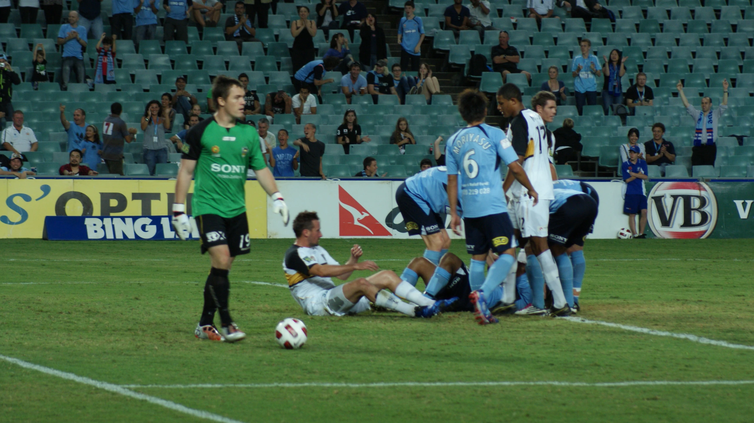 several young men playing a soccer game in front of a large crowd