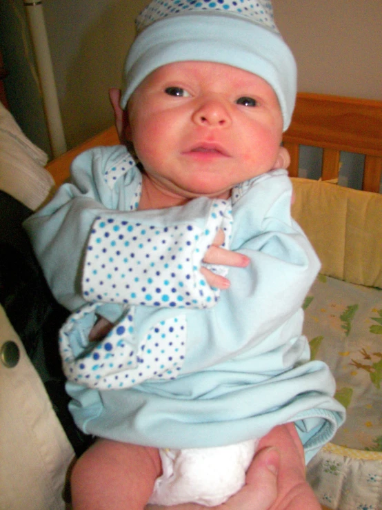 a close up of a baby wearing a blue hat and jacket