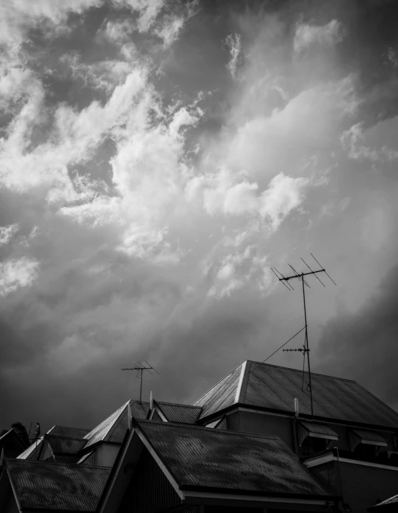 an overcast and cloudy sky with the roof of a house