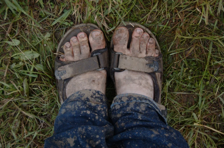 dirty feet and legs in sandals laying on the grass