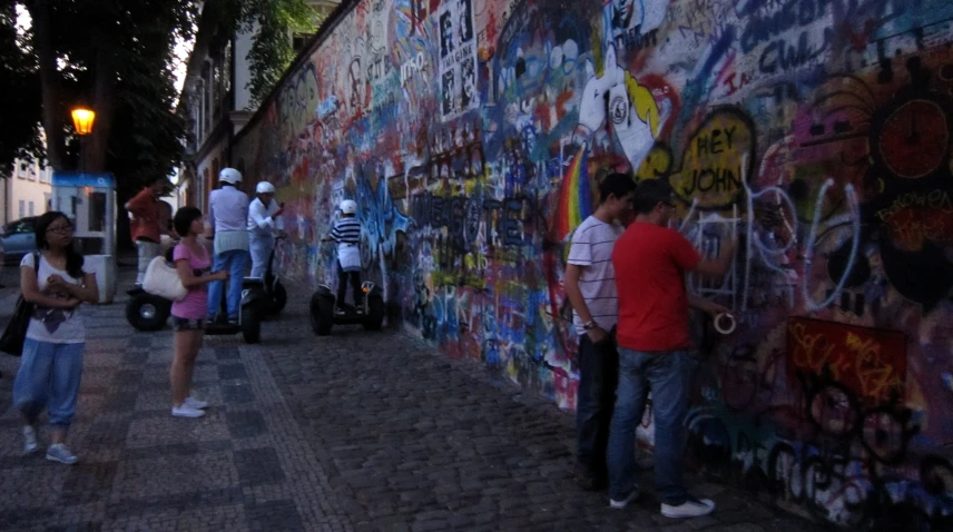 many people are standing by a wall with graffiti