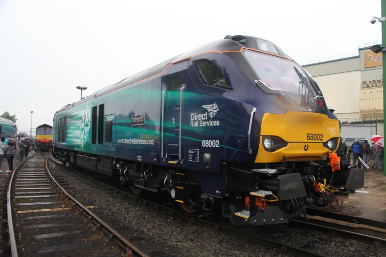 a blue train engine pulling its yellow car