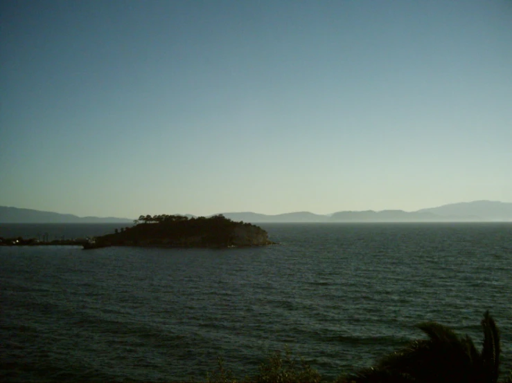 an island near the ocean with a small hill in the distance