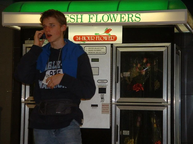 a man standing in front of a soda machine holding a cellphone
