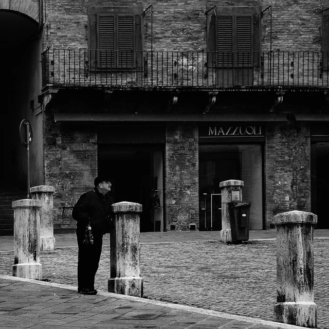 a man stands outside a small building with two pillars