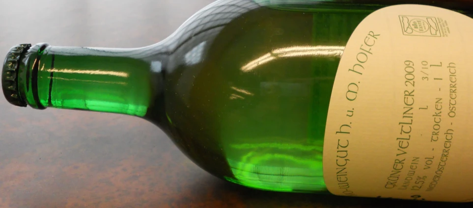 a green bottle on a wooden table with a label