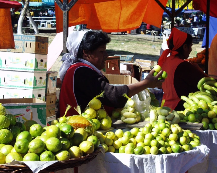 people buying fruits at an open air market