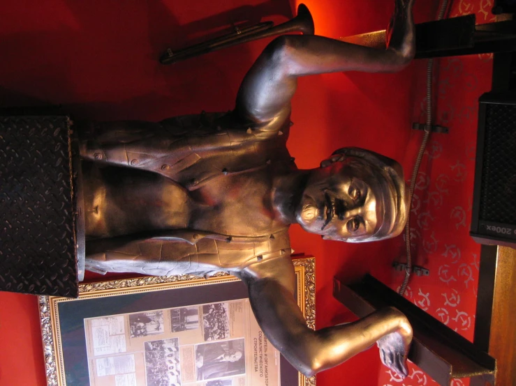 a statue in front of a red wall with several pos