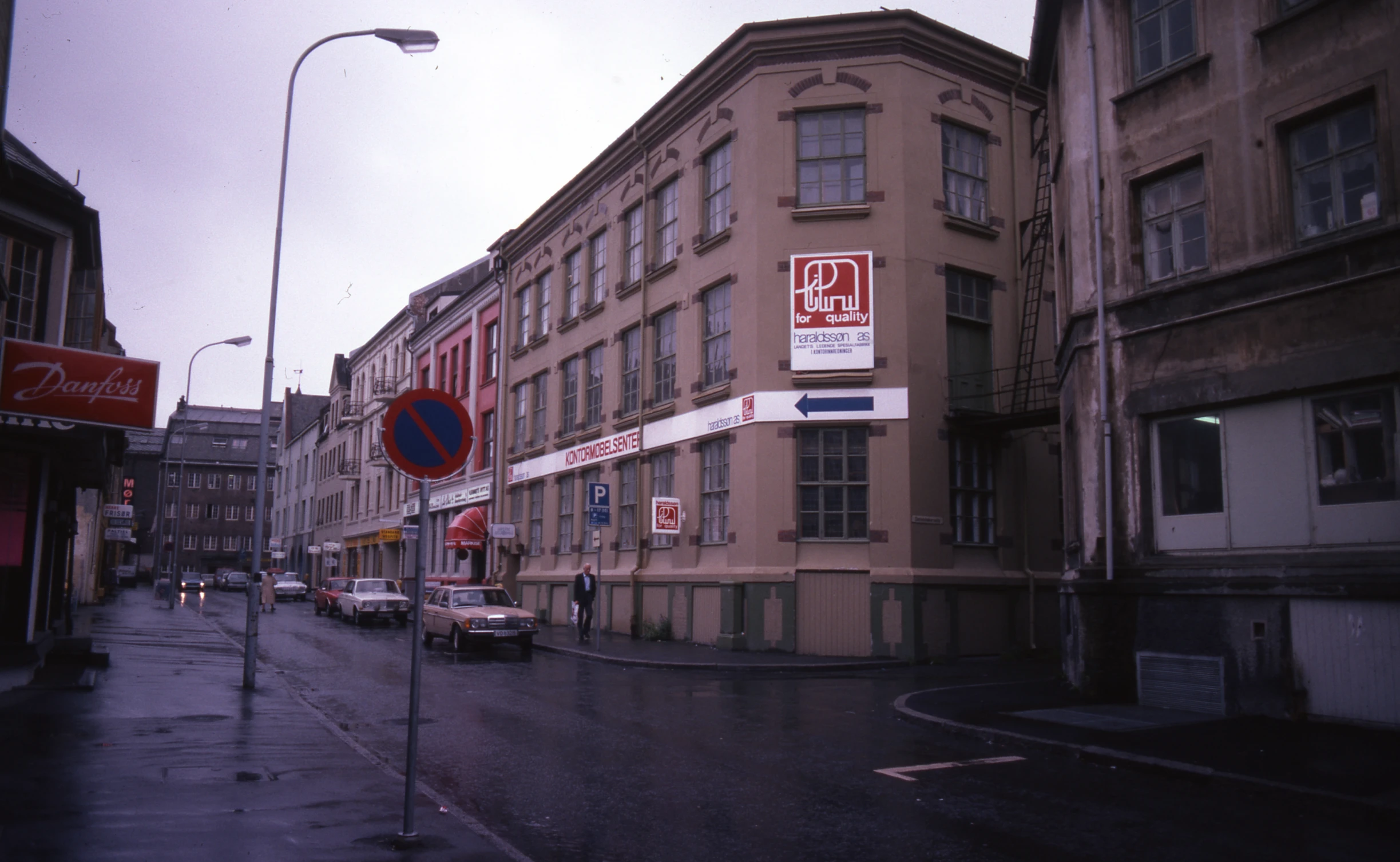 a street with several parked cars and no parking signs