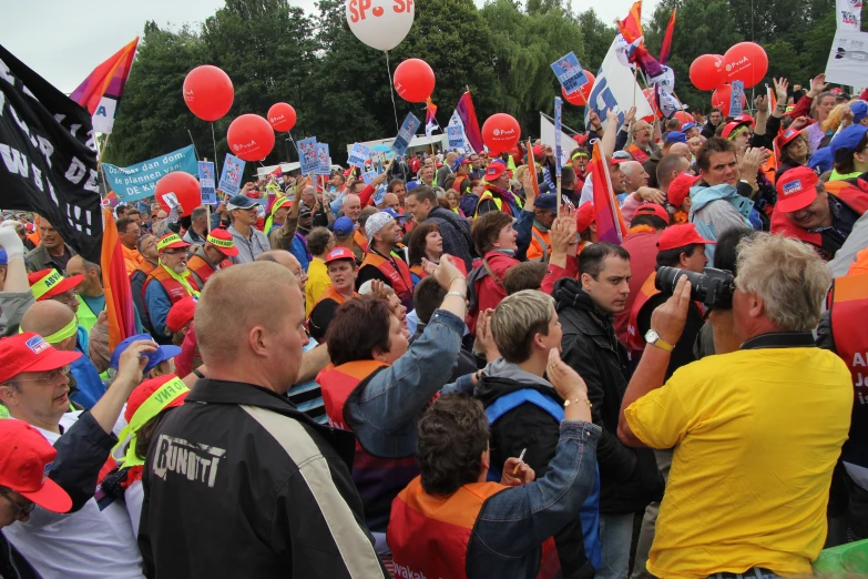 people are holding up kites and balloons during the day