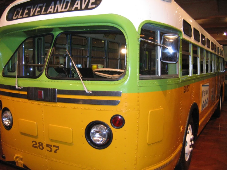 an old yellow and green bus parked in a showroom