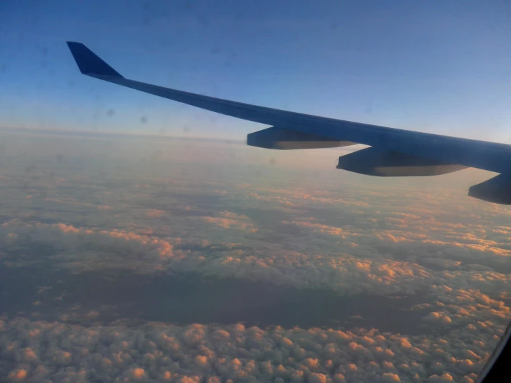 an airplane wing over some clouds in the sky