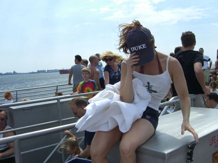 a young lady sits on the edge of a railing in front of a large group of people