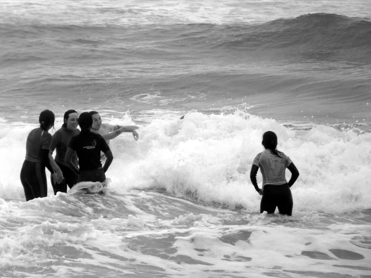 some people in wetsuits standing in water next to a wave