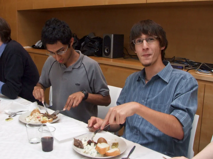 a couple of people sit at a table  into a cake