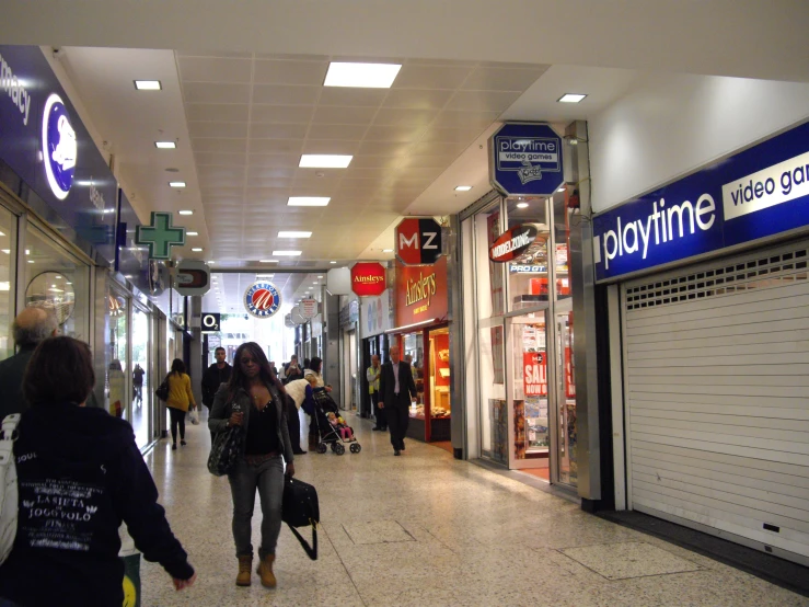 a couple walking up stairs holding suitcases in front of stores