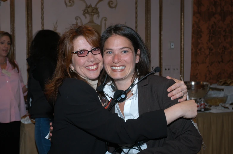 two women emcing each other in front of table with plates and silverware