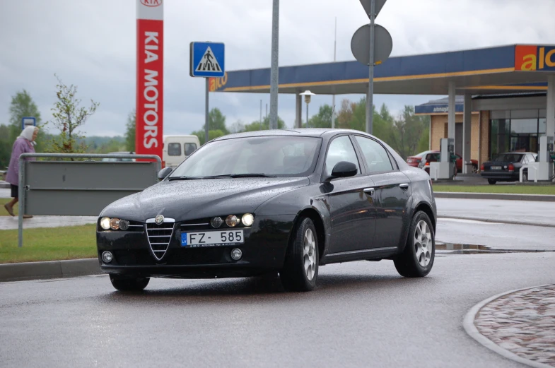 there is a black car parked at a gas station