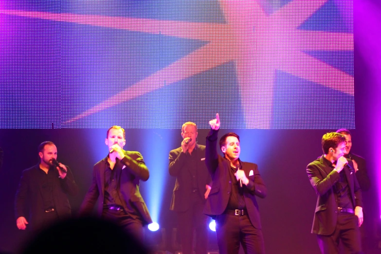 an image of a group of guys singing on stage