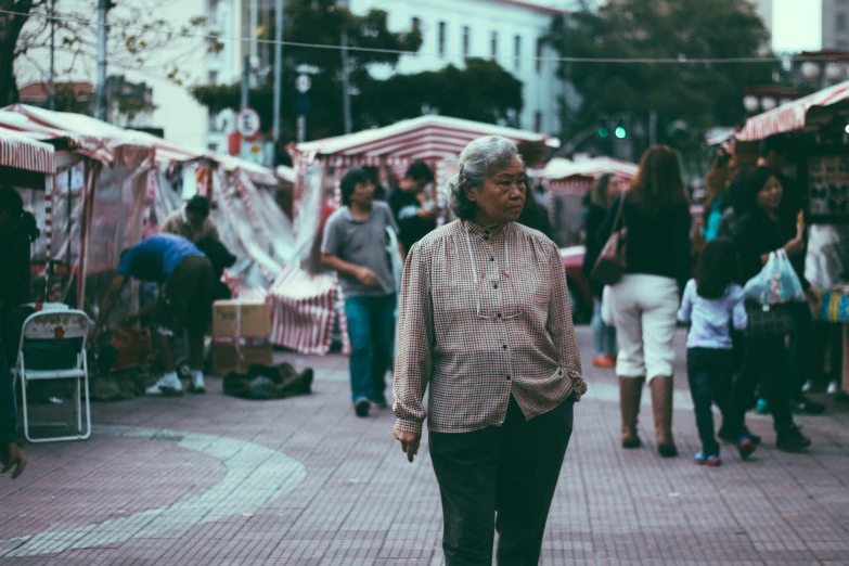 a woman walking down the sidewalk in a crowded market