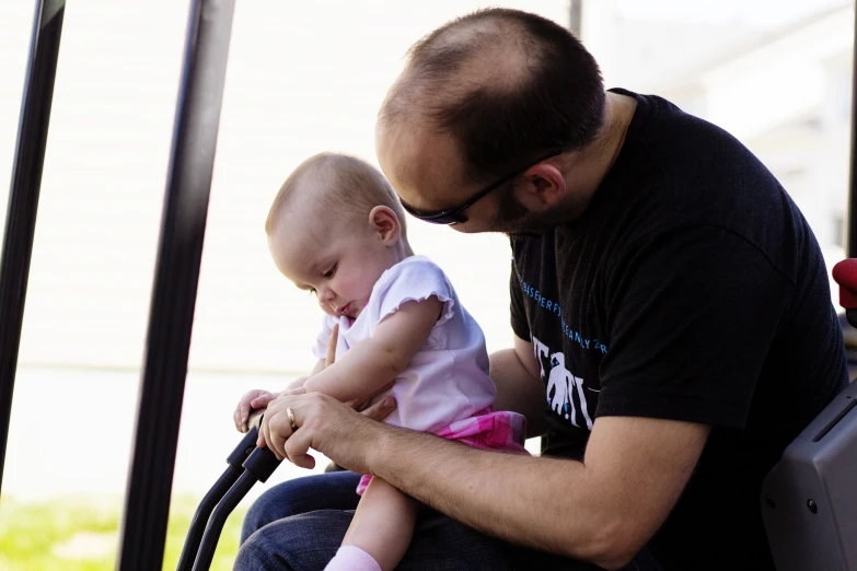 a man holding a baby sitting on a bench