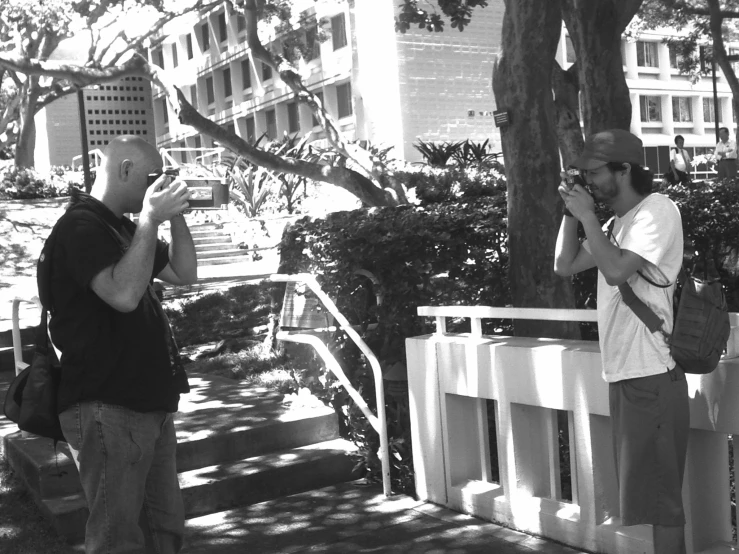 two men standing near each other holding cell phones