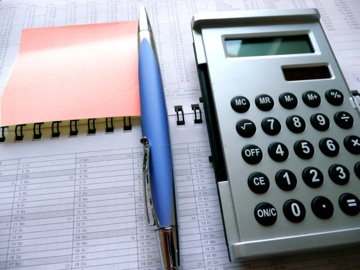 a pen, calculator, and clipboard sitting on top of papers