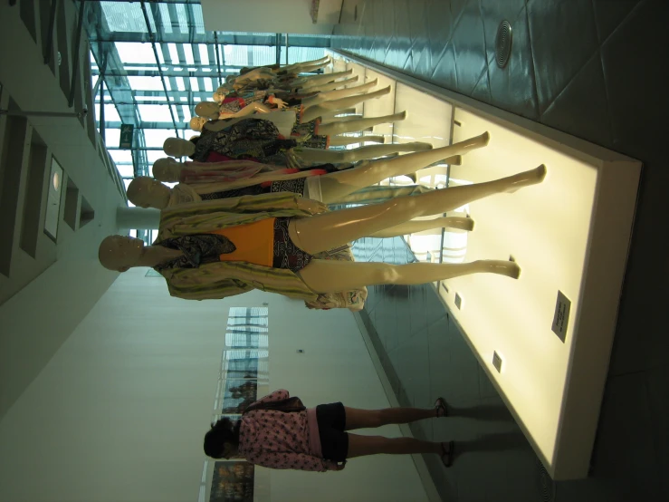 a long line of mannequins with a person standing in front of them