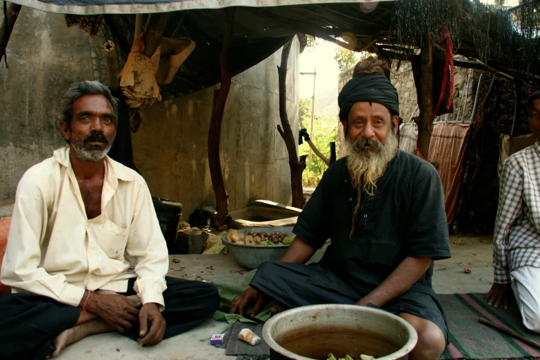 three men sitting next to each other near a building