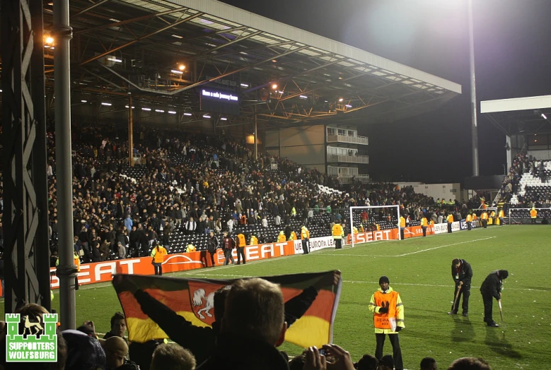 two men holding a german flag are standing on a soccer field