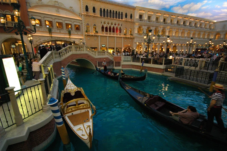 several gondolas at the edge of a canal with people in them