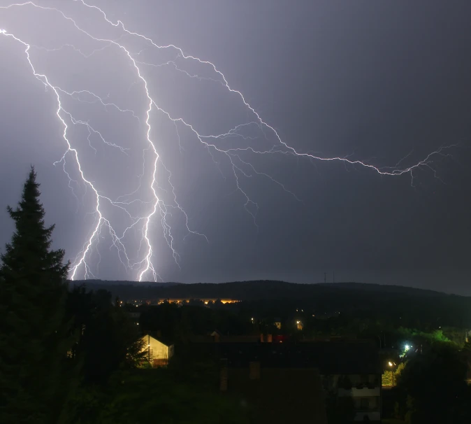 lightning striking over the city at night with buildings and houses