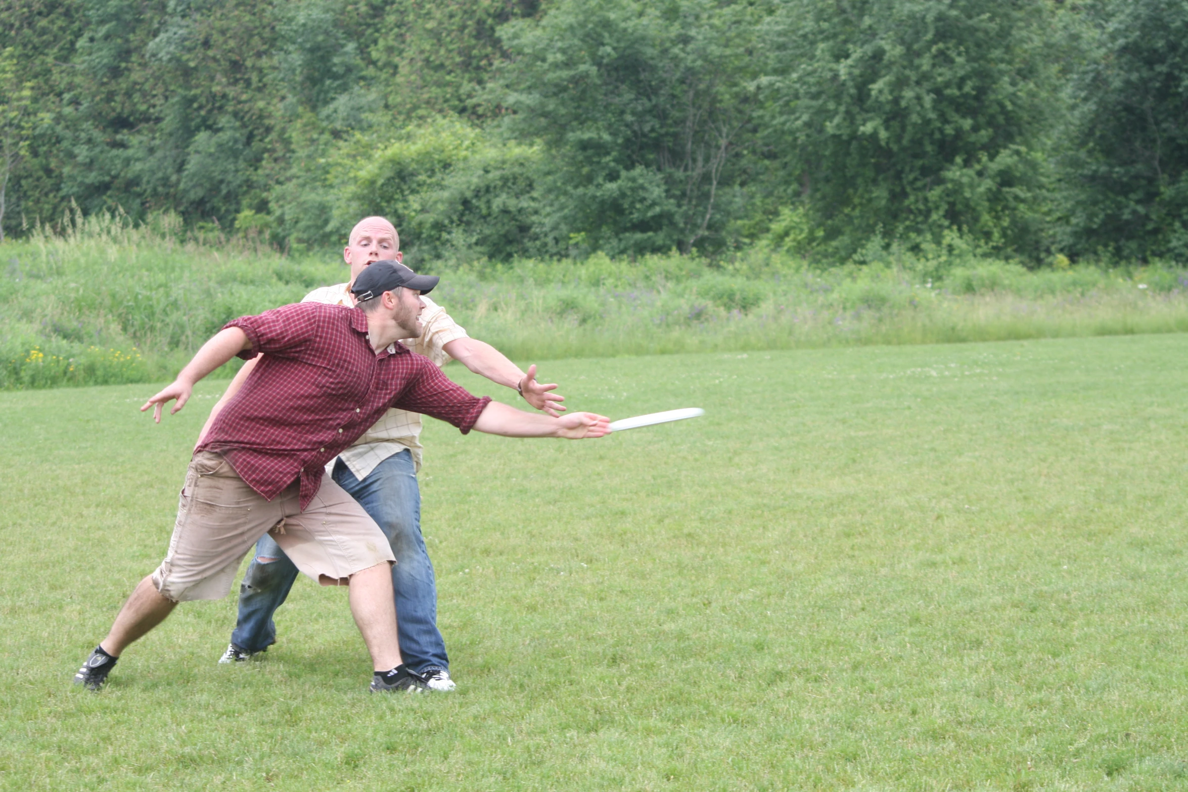 two people standing in a park playing frisbee