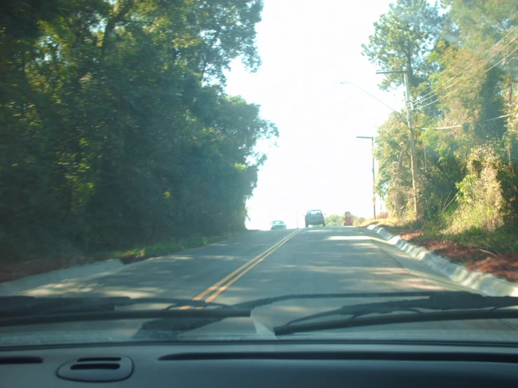 the view from inside a car looking at a country road