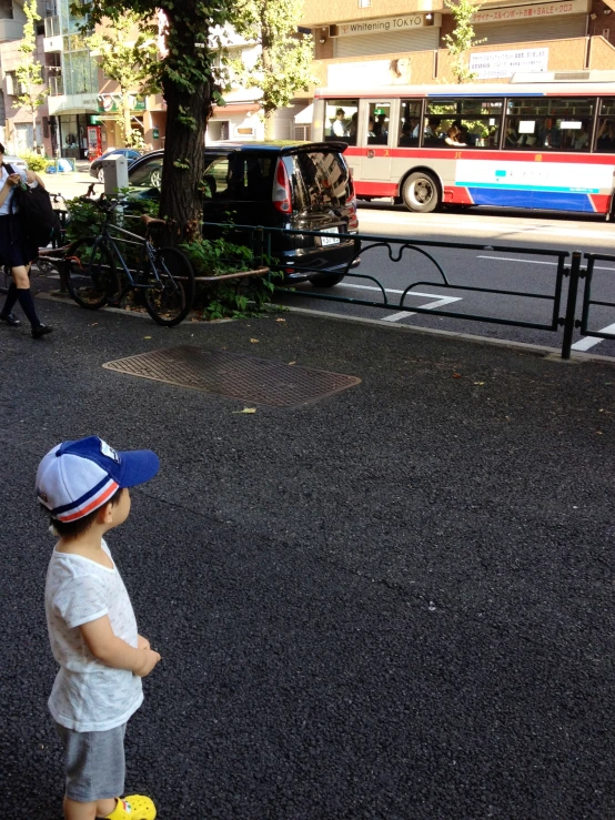 a small child watches cars pass by in the city