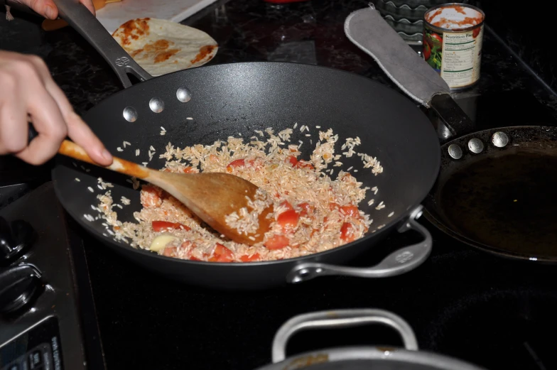 the woman is stirring in a pan full of vegetables